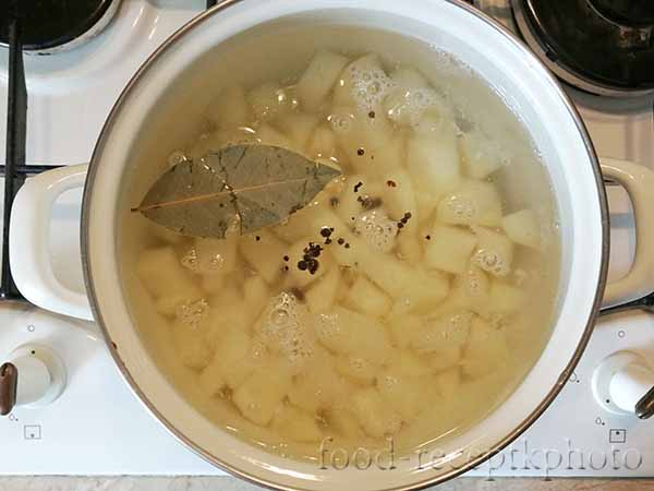 На фото в кастрюле нарезанный картофель в воде и перец с лавровым листом