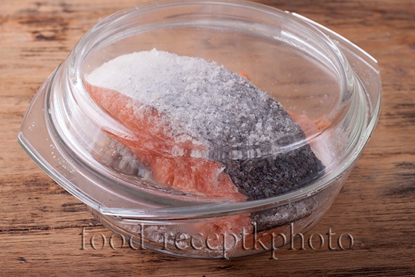 На фото стейки семги обсыпанные солью в стеклянном контейнере для засаливания в домашних условиях