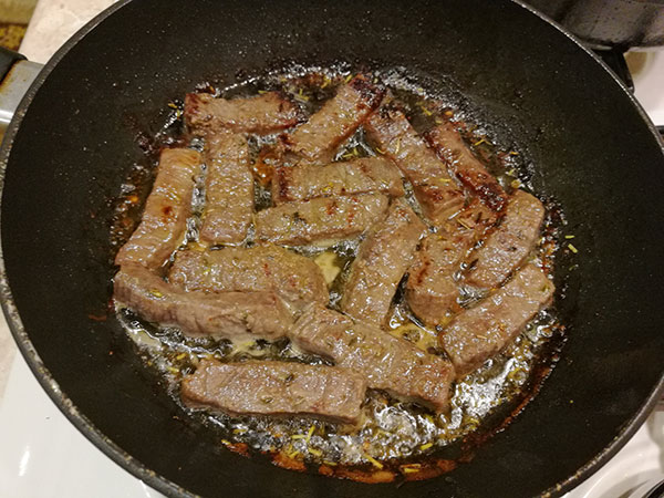 На фото в сковороде жарится мясо с луком
