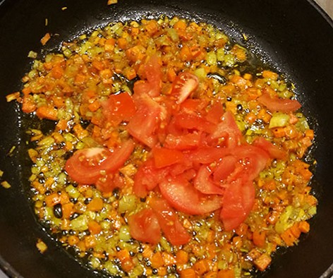 На фото в сковороде обжаривается репчатый лук,морковь,помидор и чеснок