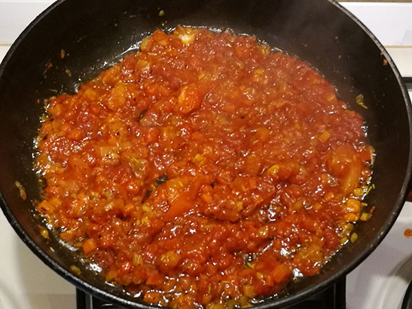 На фото в сковороде обжаривается репчатый лук,морковь,помидор и чеснок с томатной пастой