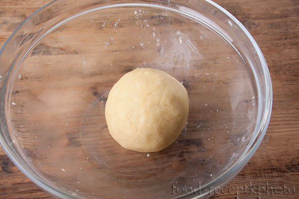 На фото в стеклянном салатнике готовое песочное тесто в виде шара