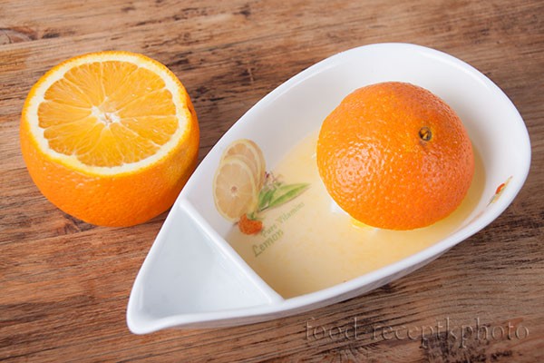 На фото разрезанный апельсин и соковыжималка для цитрусовых