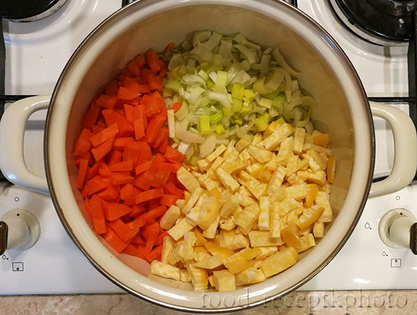 На фото в кастрюле нарезанные овощи моркови, репы и лука порея