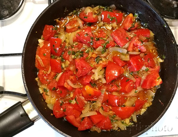На фото в сковороде жарится лук и помидоры