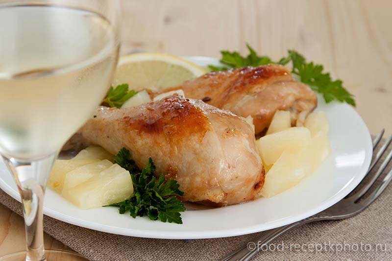 Жареные куриные ножки в белой тарелке и бокал белого вина