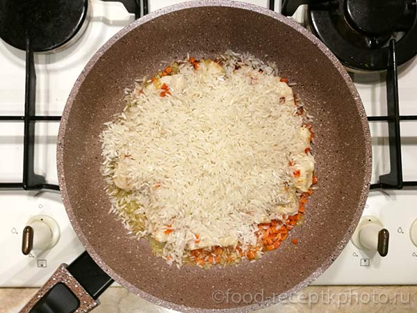 Лук,филе ,рис и морковь в сковороде для приготовления плова с курицей